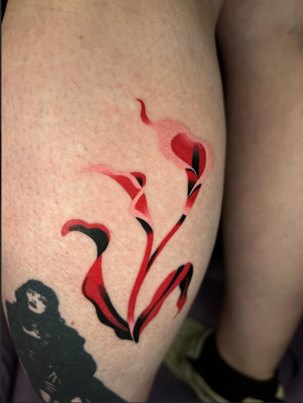 Red calla lily tattoo on a calf