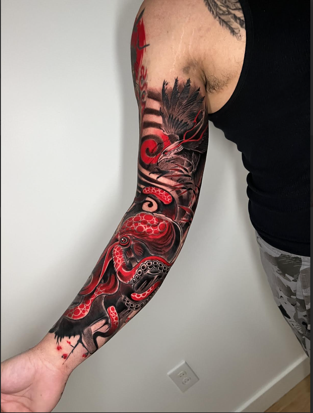Full color arm sleeve tattoo with a red octopus and bold linework