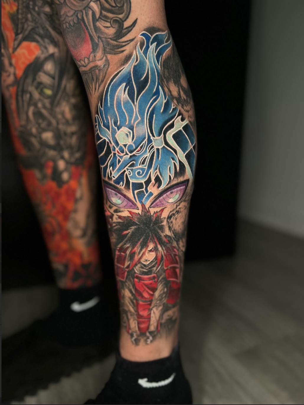 Anime tattoo detail with blue energy effects and red armor